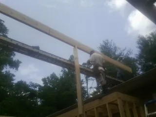 Carpenter setting a ridge beam over a new addition frame — Ice Dam Removal by Roofing Brothers in Haskins