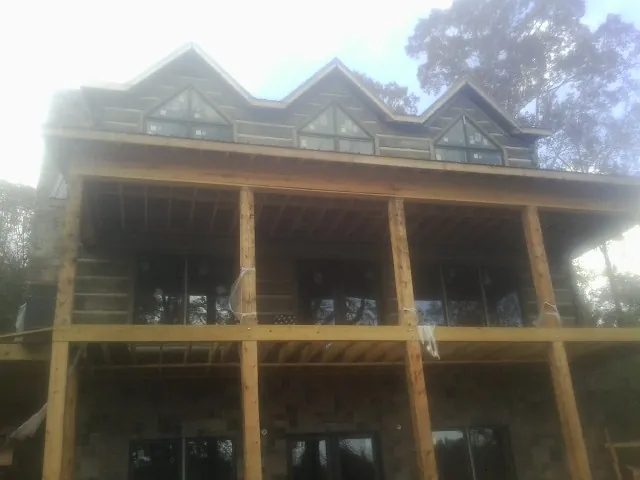 Dormers and porch framing on a large log home under construction — Roof Coating work by our crew in Haskins